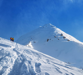 游客们在前往白雪覆盖的山顶的途中。冬季远足