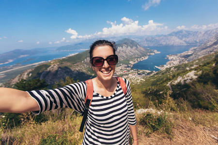 微笑的年轻妇女采取自拍在背景山和蓝色海风景地平线.