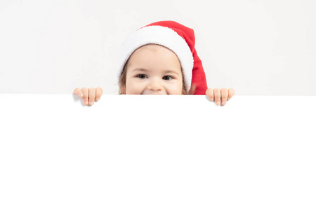 快乐的小女孩在圣诞老人帽子被隔绝在白色背景上的肖像