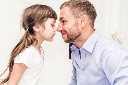 小女孩和爸爸一起在家里笑着摸鼻子。爱家庭和父亲日概念