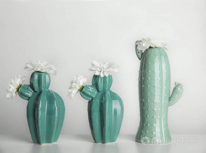 时尚的仙人掌形状的花瓶, 桌子上有花, 反对轻墙。创意装饰