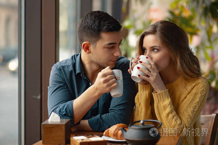 年轻的夫妇约会在咖啡店有一个谈话, 享受彼此度过的时间