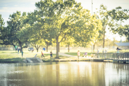 复古色调运动模糊的家庭孩子钓鱼附近木码头码头在湖池塘。由邻里协会赞助的免费社区活动。散焦人在城市公园湖畔钓鱼