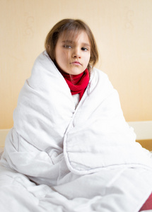 用白色的毯子覆盖悲伤生病的女孩
