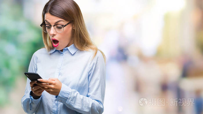 年轻美丽的女商人用智能手机在孤立的背景上发短信吓得心惊肉跳害怕和