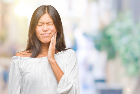 年轻的亚洲妇女在孤立的背景下触摸口与手与痛苦的表达, 因为牙痛或牙科疾病的牙齿。牙医概念