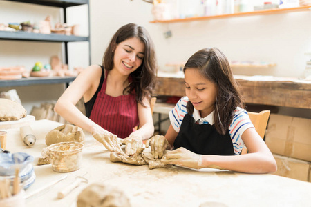 妇女和女孩揉黏土在陶瓷车间餐桌上制作艺术产品照片