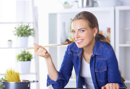 烹饪健康食品保温锅与蔬菜的年轻女子是它。健康的生活方式，在家里做饭的概念