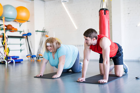 全长画像超重妇女在健身房健身锻炼与私人教练帮助她