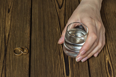 女性手拿一杯酒, 特写, 木质背景, 复印空间照片