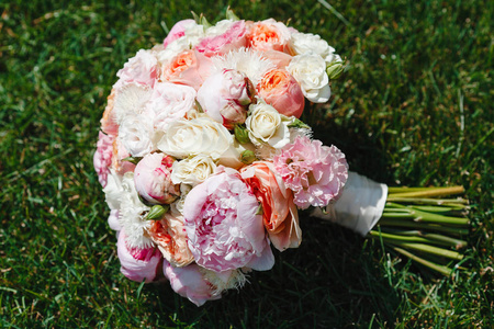 美丽的花束, 从华丽的牡丹花和玫瑰盛开躺在绿草特写镜头。婚礼当天新娘配件