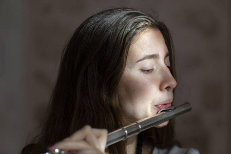 一个美丽的女人摆在演奏的长笛流派年轻美丽的 girlr 特写肖像照片