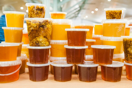 蜂蜜在玻璃罐子和瓶子站在柜台上。销售美味健康产品