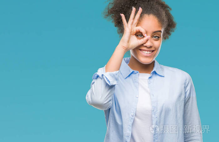 独立背景的年轻美国黑人妇女做 ok 手势用手微笑, 眼睛看通过手指与