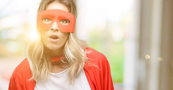 年轻的超级英雄女人戴着斗篷吓得发抖, 表示恐慌和恐惧照片