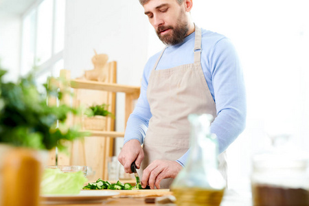 在家里宽敞的厨房里, 在厨房里, 复制空间里, 漂亮的成熟男人烹饪沙拉和切菜的中段肖像
