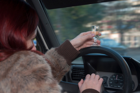 伏特加女醉酒的女人开车与伏特加酒在手照片