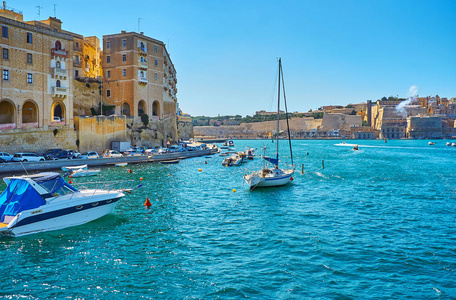 停泊的游艇在 Vittoriosa 码头的蔚蓝水域上摆动, 在背景上的老森格莱阿和瓦莱塔城墙上的看法, Birgu, 马耳他