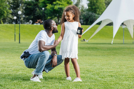 非洲裔美国人女儿在公园里拿着父亲警徽