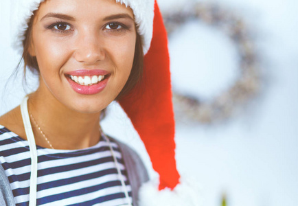幸福快乐的笑的年轻女人玩的愉快和圣诞准备穿上圣诞老人的帽子