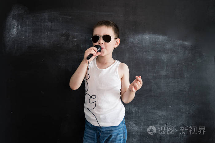 小男孩站在黑板旁边, 用麦克风唱歌.明星.未来职业的创意设计理念