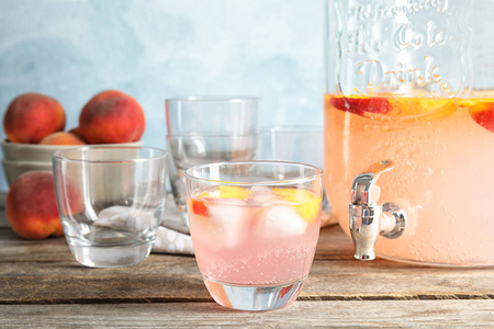 桃鸡尾酒在玻璃和罐子与水龙头在桌上。提神饮料