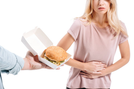 显示胃痛的金发女子的裁剪图像, 男子建议不健康的汉堡查出的白色