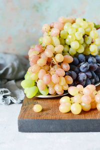 三种新鲜成熟的葡萄在灰色背景下。收获。新鲜的夏日水果。甜水果甜点