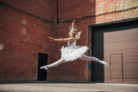 在城市街道上跳的美丽的年轻芭蕾舞女演员