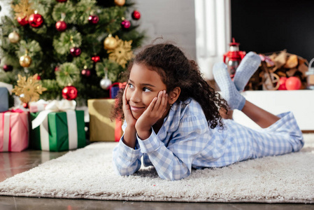 可爱的非洲裔美国儿童在睡衣躺在地板上, 看着离家, 圣诞节概念