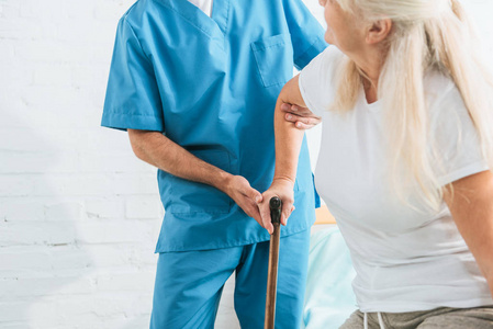 男性护士支持老年女性手杖的裁剪拍摄