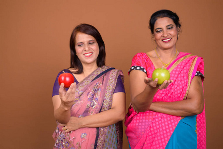两个快乐的印度妇女持有健康苹果水果