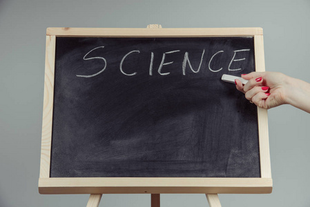一位老师写科学，用手在黑暗的黑板上绘制化学元素，灰色背景