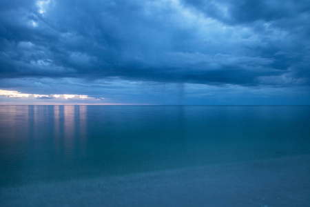 雨从乌云上倾泻而下, 在那不勒斯的海蛤湾海滩, 日落时分的佛罗里达