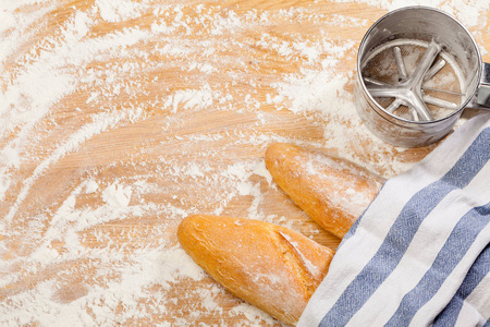 新鲜出炉的手工面包 法式面包 用毛巾覆盖面粉筛子或筛子在木制背景上覆盖面粉