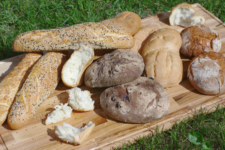 Assortiment 新鲜的面包, 长棍, 面包在一个木制的立场上的绿色草的背景