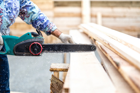 框架锯工人, 伐木工人或勤杂工切割木材木板用电动链锯照片