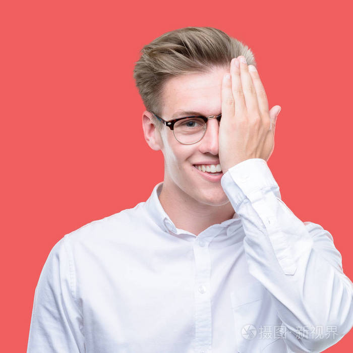 年轻英俊的金发男人用手捂着一只眼睛脸上充满自信的笑容和惊喜的情绪