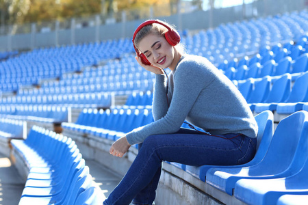 在体育场听音乐的美丽的年轻妇女