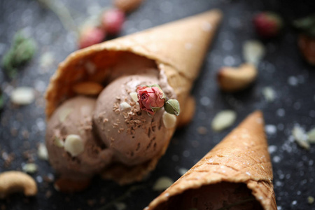 尼斯 designigned chokolate 冰淇淋在 tabble 与坚果和糖 pund 和玫瑰在黑底华夫饼杯