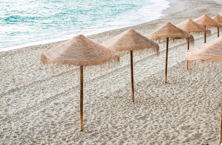 在空旷的海滩上的稻草阳伞。塞维利亚西班牙
