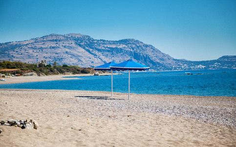 希腊罗得岛海滩上的两把蓝色雨伞