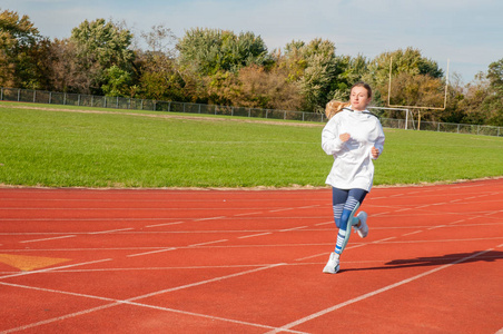 健康的生活方式年轻健身妇女跑步。女子田径跑步者在田径赛道上的练习