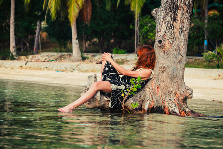 女人坐在热带海滩上和树