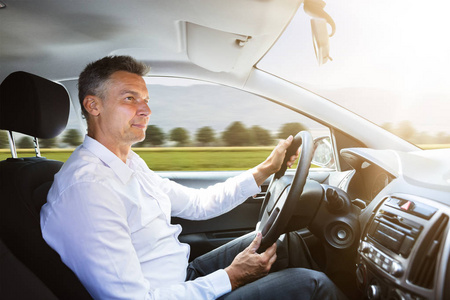 一个快乐的男性司机驾驶汽车的侧面视图照片