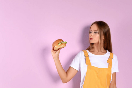 苗条的女人与汉堡的颜色背景。健康饮食