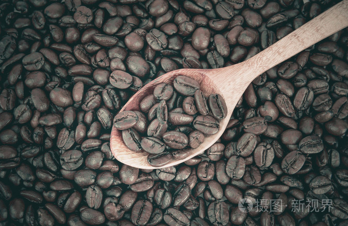 在木勺烘焙过的咖啡豆放咖啡豆作为背景
