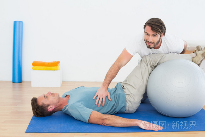 物理治疗师协助年轻人与瑜伽球