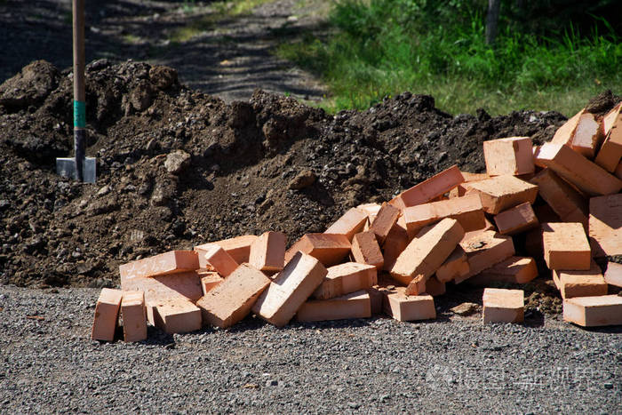 为建筑工作准备砖块躺在铁锹和绿草旁边建设和成就夏天