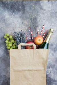 葡萄酒水果花卉为晚会或野餐在纸工艺包上的灰色具体背景。顶部视图
